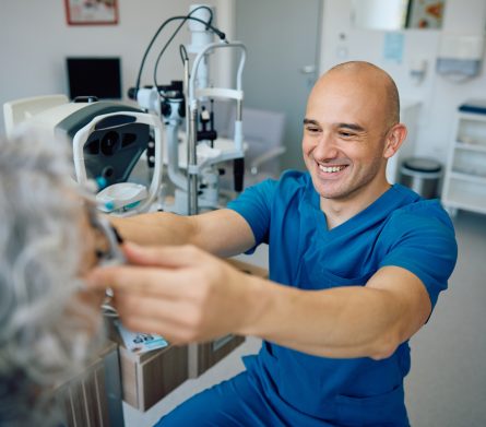 Happy ophthalmologist using optical trial frame while testing patient's eyesight at the clinic.