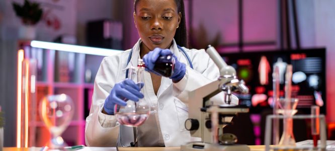 Young african scientist with test tube and microscope making research in clinical laboratory.