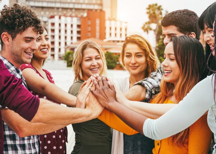 Young happy people stacking hands outdoor - Focus on hands